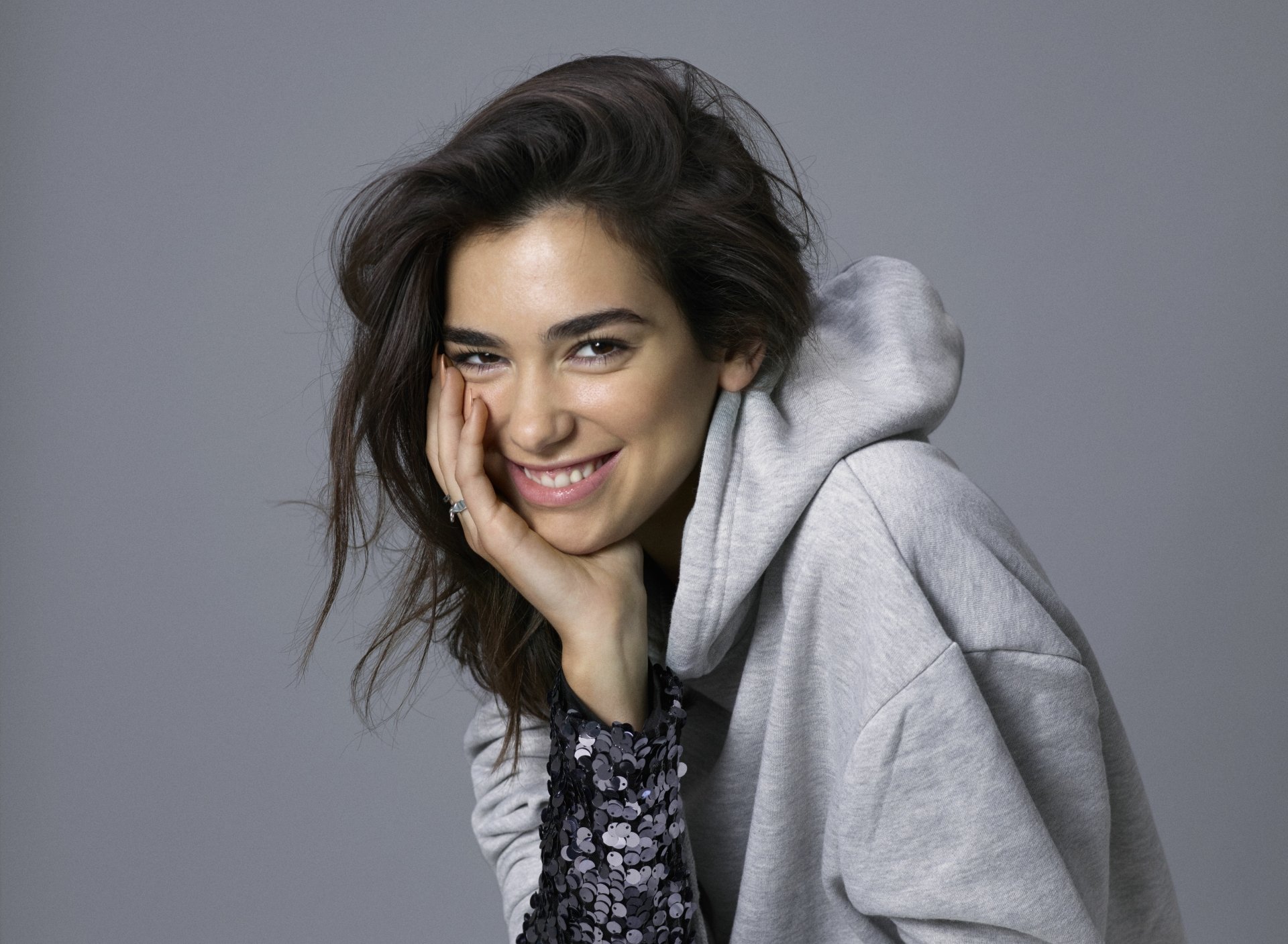 Dua Lipa smiling in a casual hoodie, captured in a high-resolution 8K Ultra HD music-themed desktop wallpaper.