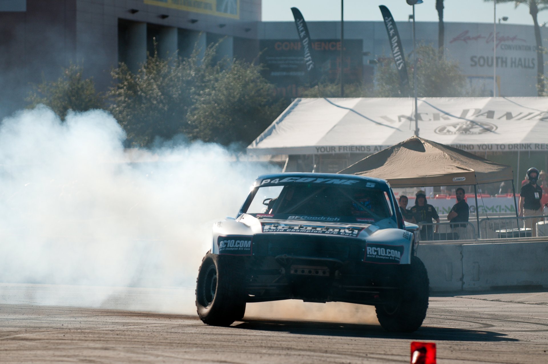 4K Ultra HD PC desktop wallpaper: rallying sports scene — a drifting rally car tearing through an urban course, smoke plumes, spectators and tents.