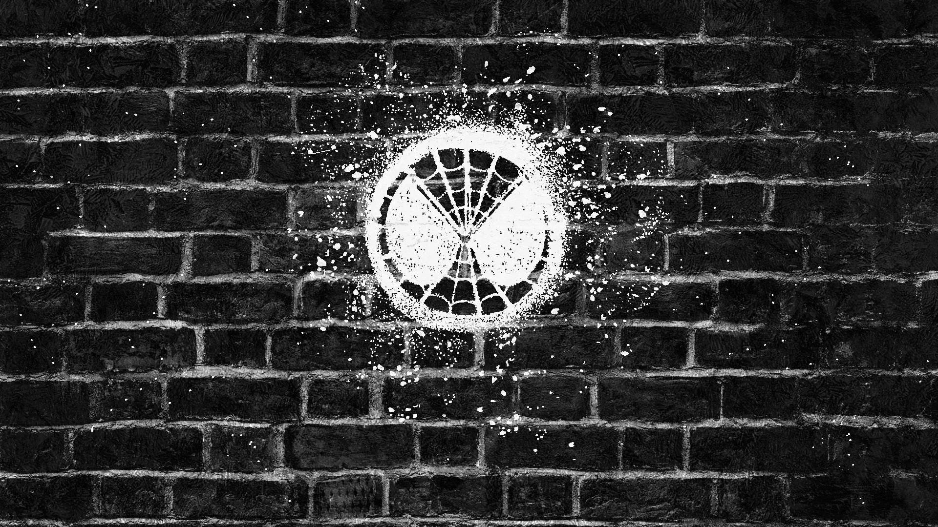HD PC desktop wallpaper featuring a white Spider-Man mask emblem spray-painted on a dark brick wall, inspired by the movie Spider-Man: Far From Home.