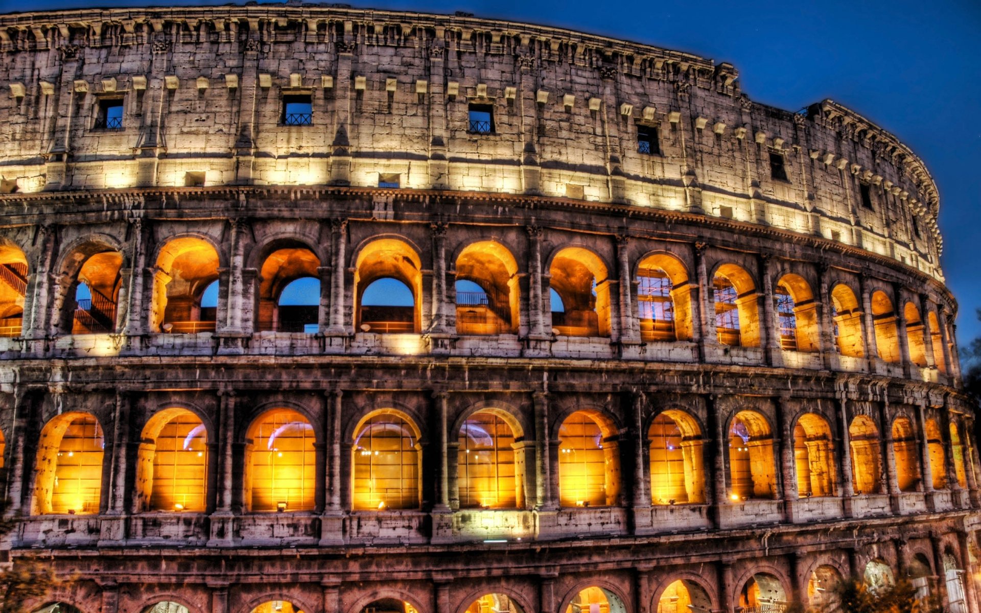 HD PC desktop wallpaper featuring a close-up view of the illuminated man-made Colosseum against a deep evening sky.