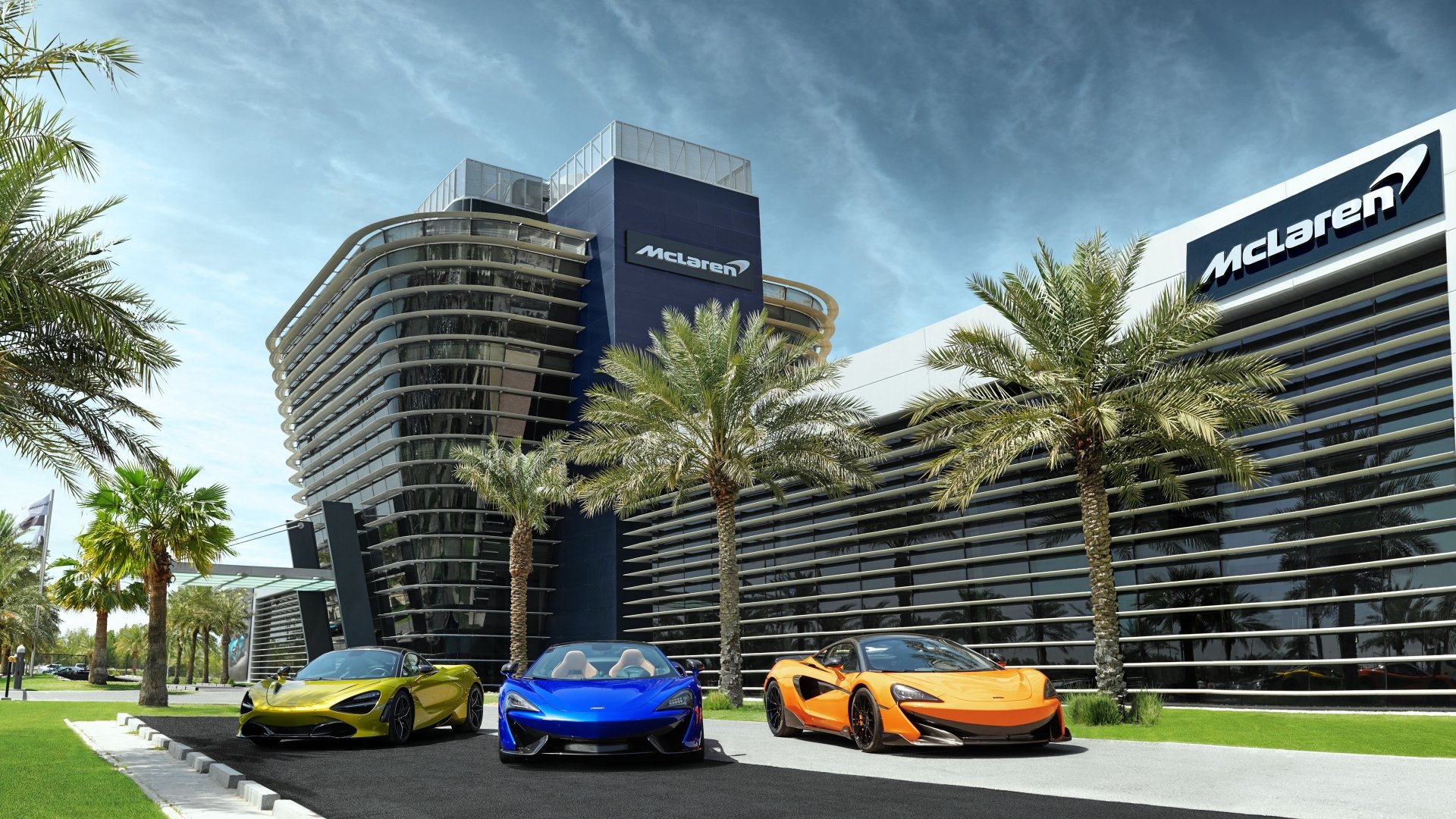 A 4K Ultra HD wallpaper featuring McLaren 600LT, 720S, and 570S supercars in orange, blue, and green parked in front of a McLaren building lined with palm trees.