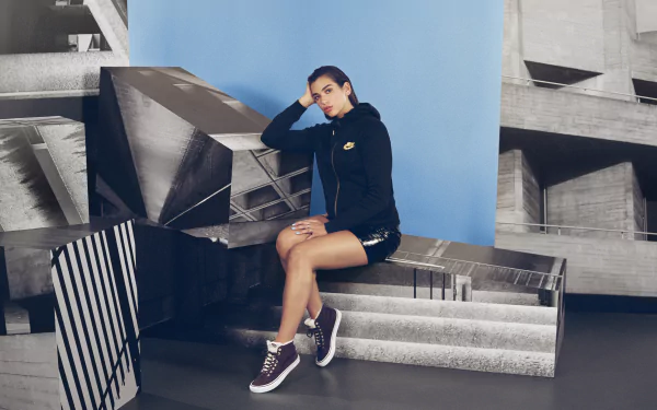 Brunette English singer Dua Lipa poses confidently in a stylish black outfit against an artistic geometric background in this 4K Ultra HD PC desktop wallpaper.