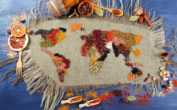 A 4K Ultra HD still life desktop wallpaper featuring a world map creatively formed with colorful herbs and spices on a textured fabric background.