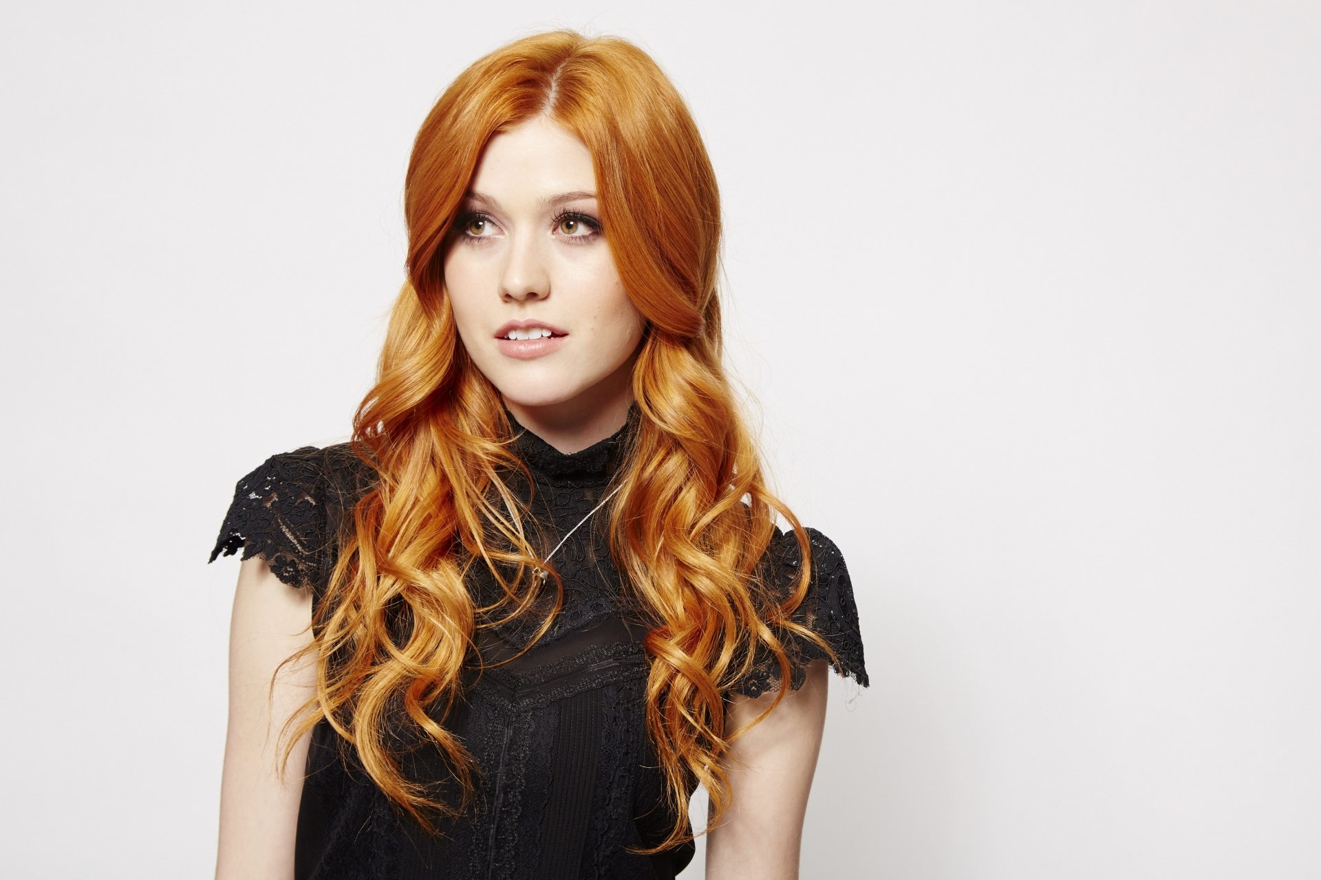 5K desktop wallpaper: portrait of a long-haired redhead woman in a black dress against a clean white background.