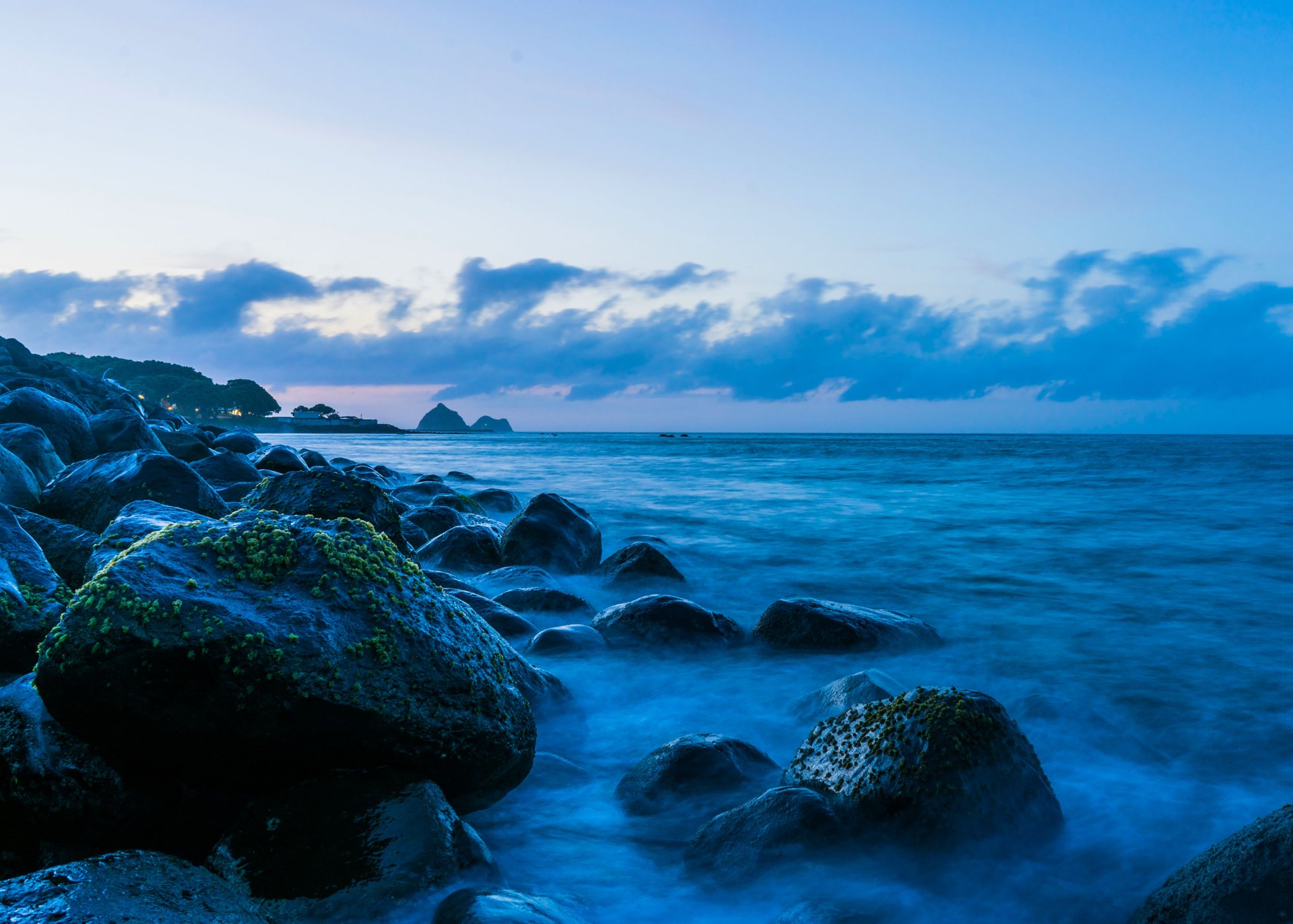 A serene coastline with rocky shorelines meeting the ocean under a vast horizon, captured in 4K Ultra HD as a nature-themed desktop wallpaper.