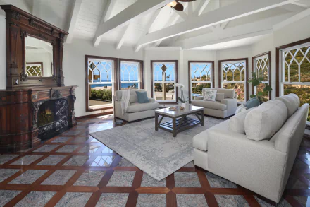 Spacious living room with man-made furniture, large windows offering ocean views, and exposed ceiling beams, captured in a 4K Ultra HD PC desktop wallpaper quality.