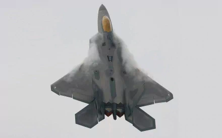 Lockheed Martin F-22 Raptor military jet captured mid-flight, shown with vapor trails, featured as an HD PC desktop wallpaper and background.