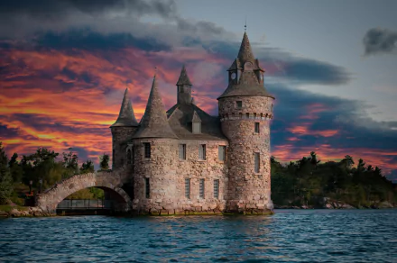 Boldt Castle, a man-made stone fortress with pointed towers, stands against a dramatic sunset sky over calm waters in this 4K Ultra HD desktop wallpaper.