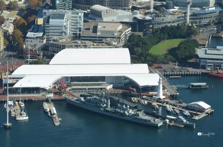 Aerial view of the HMAS Vampire (D11) destroyer displayed at the Australian National Maritime Museum, surrounded by docks and modern buildings.