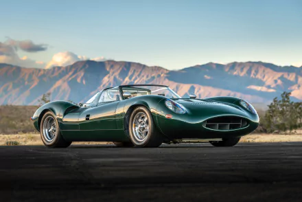 Green Jaguar XJ13 race car roadster parked on an open road with mountains in the background, shown in 4K Ultra HD PC desktop wallpaper quality.