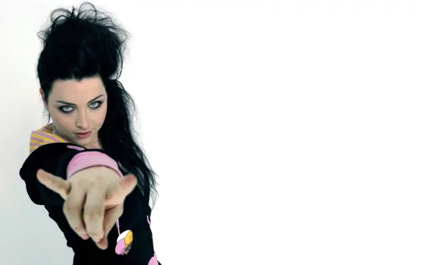 A striking HD wallpaper featuring Amy Lee, her dark hair cascading as she poses confidently, pointing directly at the viewer against a blank background.