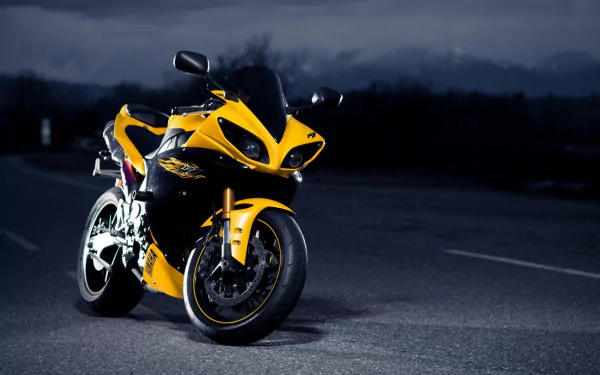 A yellow Yamaha YZF-R1 motorcycle parked on an asphalt surface at night, featured as an HD PC desktop wallpaper and background.