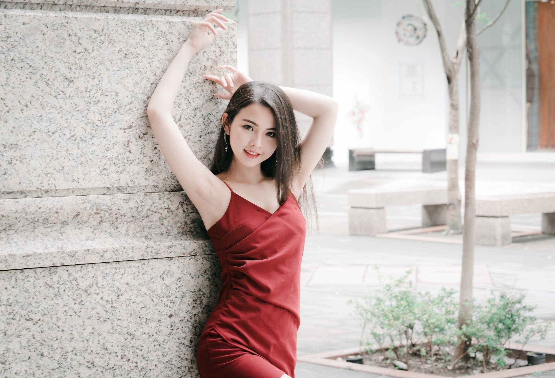 A brunette woman in a red dress poses elegantly against a textured wall, making this HD desktop wallpaper visually appealing.