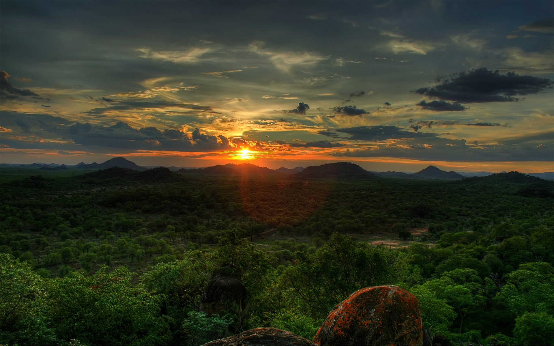 HD desktop wallpaper capturing a vibrant sunset over lush green hills in Zimbabwe, Africa, with dramatic clouds enhancing the natural beauty.