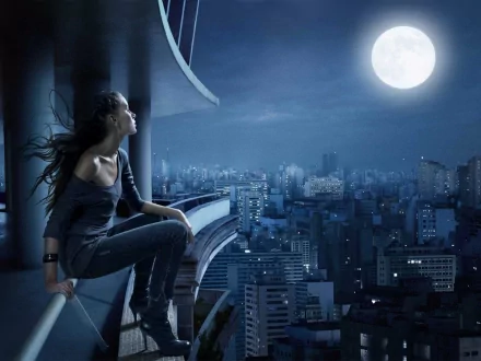 A woman in dark attire sits on a ledge overlooking a cityscape under a full moon, with the scene bathed in blue hues. HD desktop wallpaper and background image.