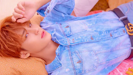 Close-up of a K-pop singer in denim reclining on a pillow, soft pastel lighting; 4K Ultra HD PC desktop wallpaper evoking Seventeen and contemporary K-pop music