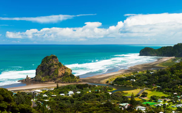 4K Ultra HD view of a New Zealand coastline featuring a coastal village, lush greenery, and ocean waves under a bright blue sky with scattered clouds.