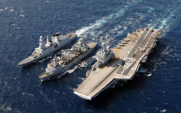 Aerial view of the French Aircraft Carrier Charles De Gaulle (R91) sailing alongside the French frigate Forbin and another warship on the open sea.