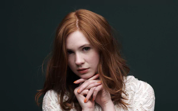HD desktop wallpaper features a close-up of Scottish redhead actress Karen Gillan with hands near her face against a dark background.