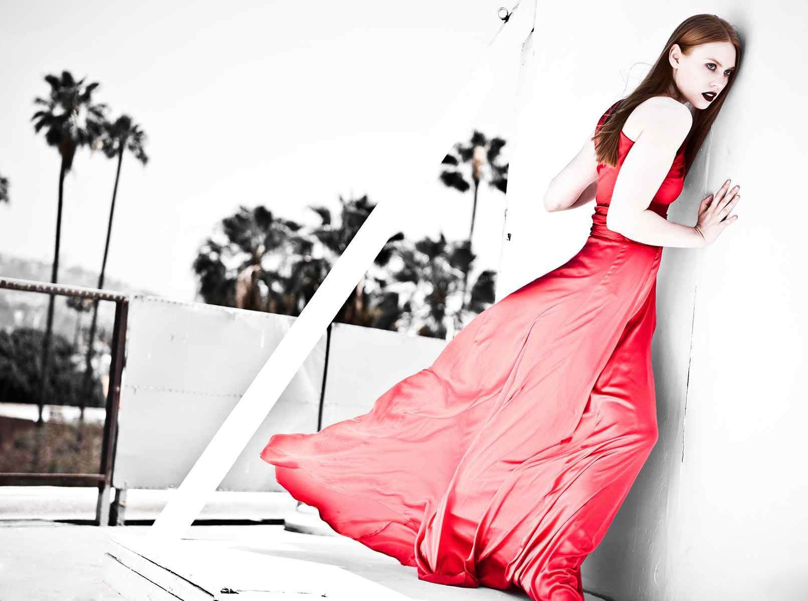A striking HD wallpaper from the TV show True Blood features a woman in a flowing red dress against a monochrome background with palm trees, exuding mystery and allure.