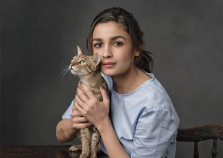 HD desktop wallpaper featuring actress Alia Bhatt, a brunette, holding a cat against a neutral background.