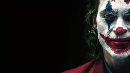 HD desktop wallpaper featuring Joaquin Phoenix as Arthur Fleck from the DC Comics movie Joker, showing a close-up of his face painted in the iconic Joker makeup against a dark background.