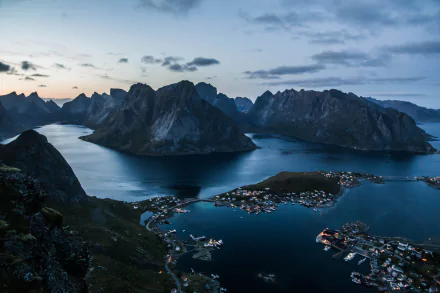 A stunning HD desktop wallpaper showcasing Reine village and sea bay in the Lofoten Islands, Norway, capturing serene twilight over dramatic mountainous landscapes.