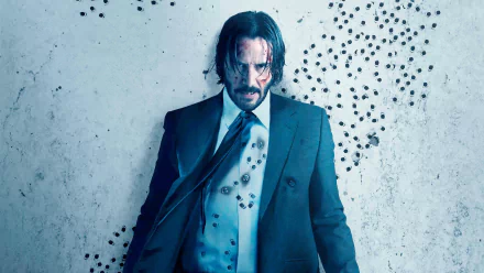Keanu Reeves as John Wick in a dramatic 4K Ultra HD movie wallpaper from John Wick: Chapter 2, standing against a wall marked with bullet holes.