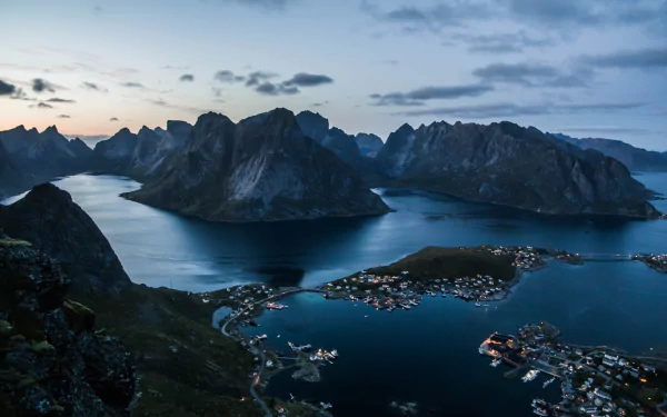A stunning HD desktop wallpaper showcasing Reine village and sea bay in the Lofoten Islands, Norway, capturing serene twilight over dramatic mountainous landscapes.