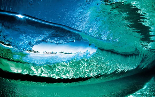 HD desktop wallpaper capturing a powerful ocean wave from beneath the water’s surface, showcasing vibrant blue and green hues of nature’s dynamic ocean waves.