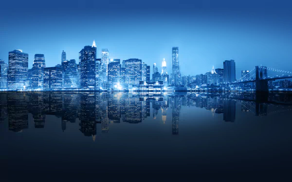 8K Ultra HD wallpaper of the illuminated New York City skyline at night, reflecting over calm water with the Brooklyn Bridge visible on the right.