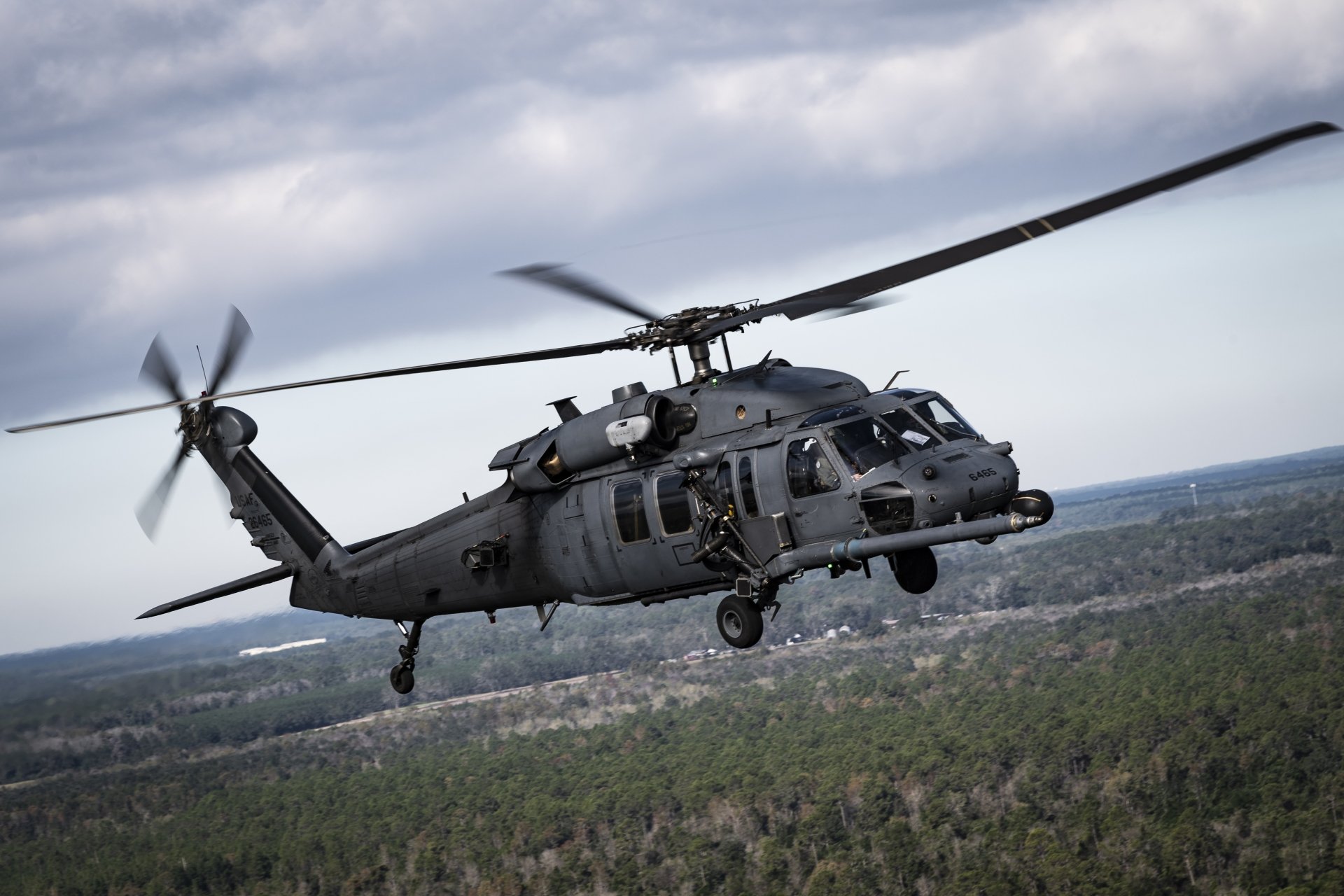 A Sikorsky HH-60 Pave Hawk military helicopter in flight over a forested landscape, captured in sharp detail for a 4K Ultra HD PC desktop wallpaper.