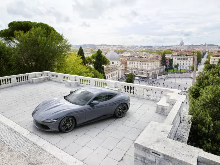 Silver Ferrari Roma supercar parked on a terrace overlooking a cityscape, captured in stunning 4K Ultra HD for a sleek PC desktop wallpaper.