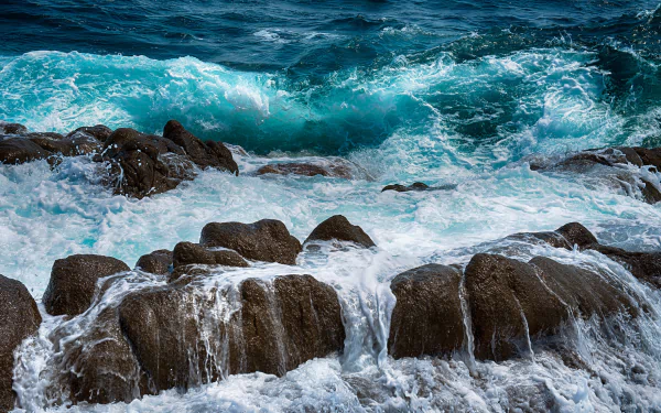 HD desktop wallpaper capturing powerful ocean waves crashing against rugged rocks, showcasing the dynamic beauty of nature and the untamed energy of the sea.