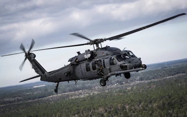 A Sikorsky HH-60 Pave Hawk military helicopter in flight over a forested landscape, captured in sharp detail for a 4K Ultra HD PC desktop wallpaper.