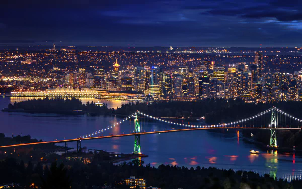 HD wallpaper featuring the Lions Gate Bridge illuminated at night against the vibrant cityscape of Vancouver, Canada. This beautifully captured image showcases a stunning man-made marvel in the urban landscape.