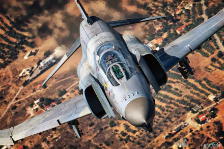 HD desktop wallpaper featuring a McDonnell Douglas F-4 Phantom II jet fighter warplane soaring over a rugged terrain, showcasing its military design and power.