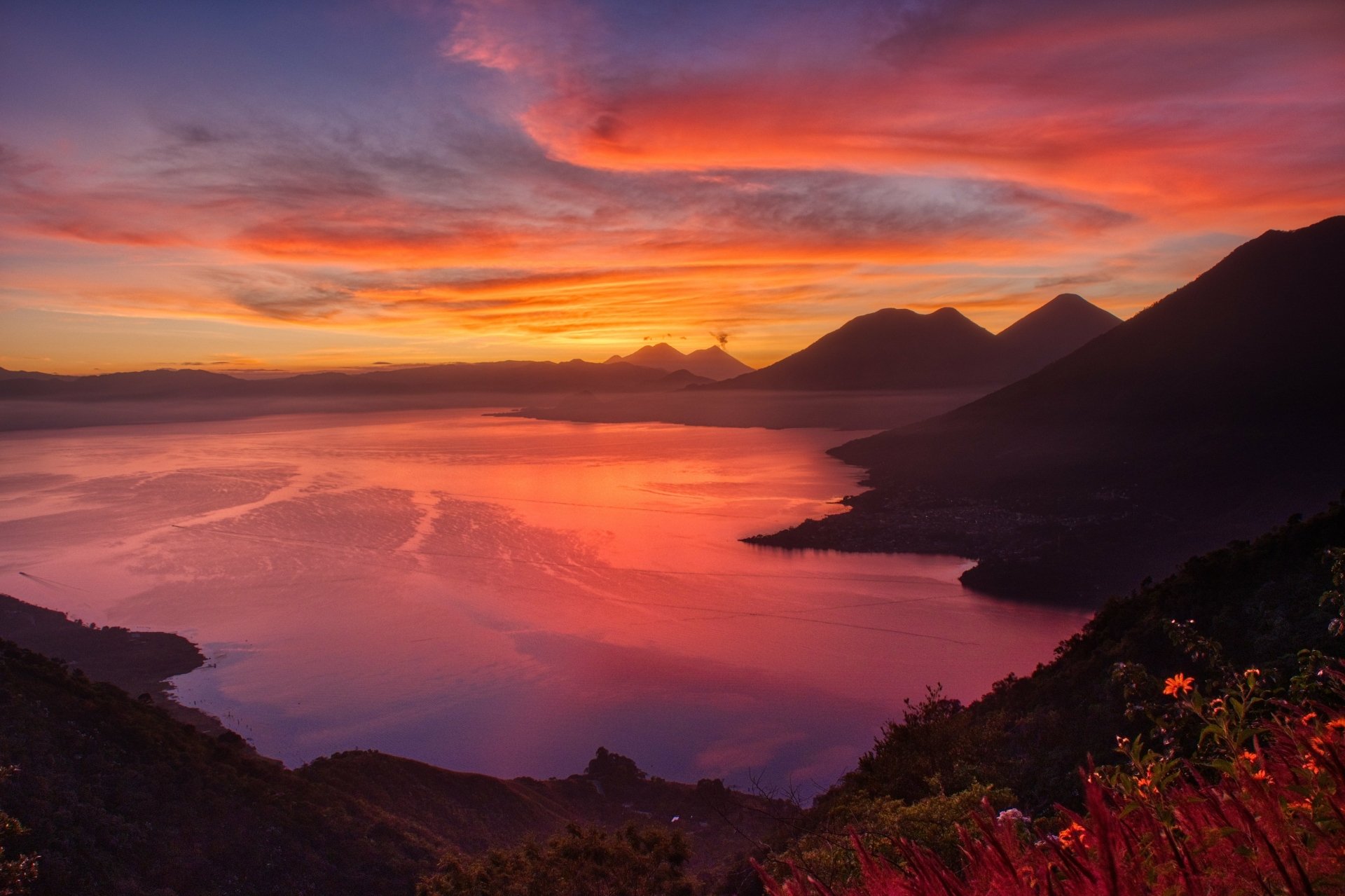 4K Ultra HD desktop wallpaper of a vibrant sunrise over a lake, with clouds reflecting colorful hues and silhouetted mountains framing the serene natural landscape.