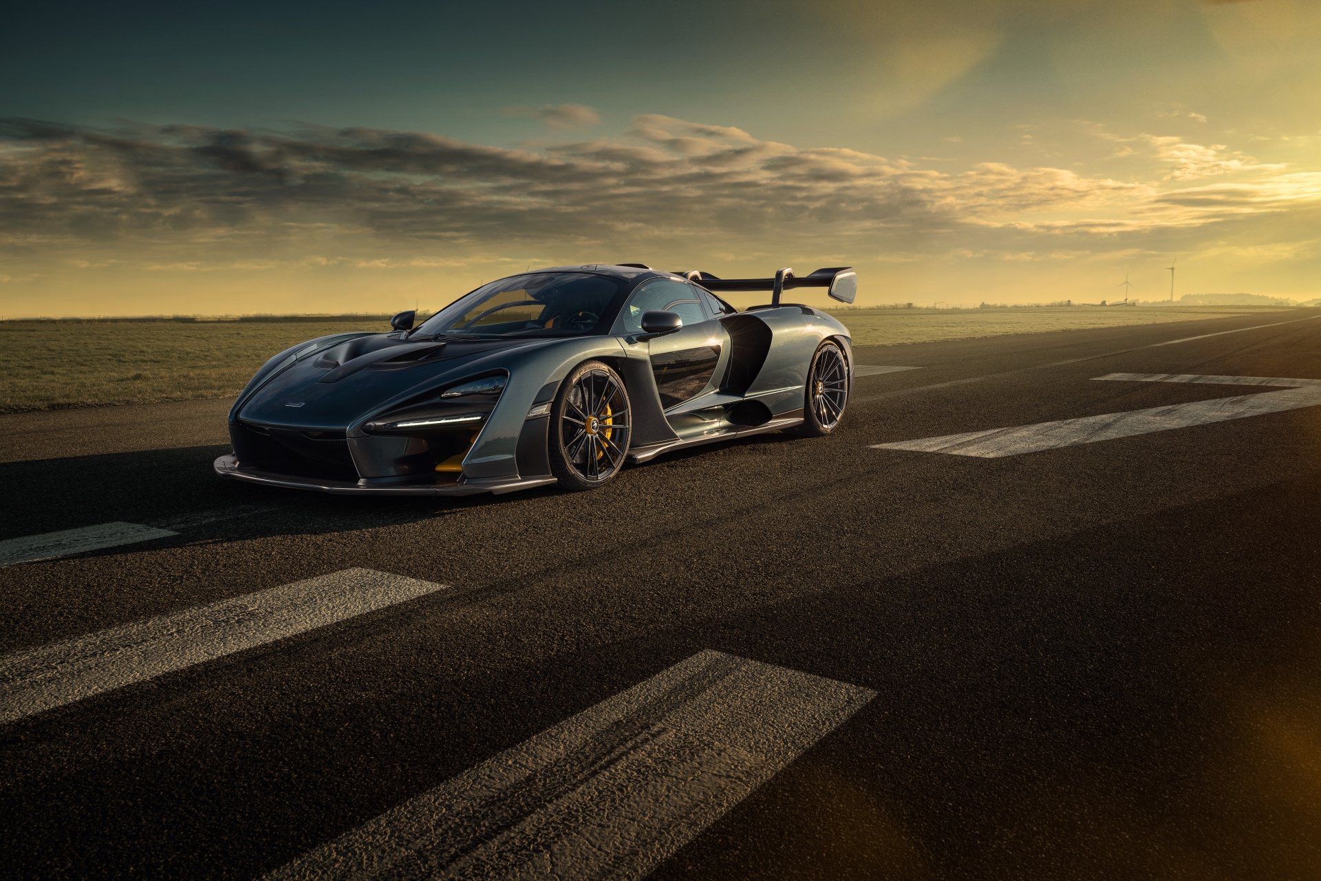 A sleek McLaren Senna supercar in 8K Ultra HD, captured on an open road at sunset, showcasing its aerodynamic design and powerful stance.