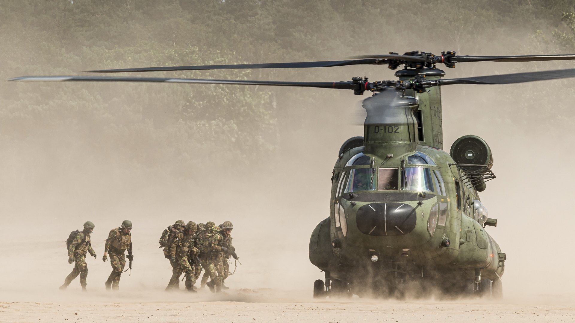 A military transport helicopter lands on dusty terrain as soldiers advance nearby, captured in stunning 4K Ultra HD for a desktop background.