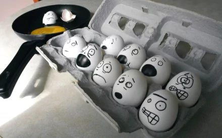 HD desktop wallpaper of eggs with various expressive faces drawn on their shells, some cracked with yolks in a pan, blending food and humor in a creative scene.