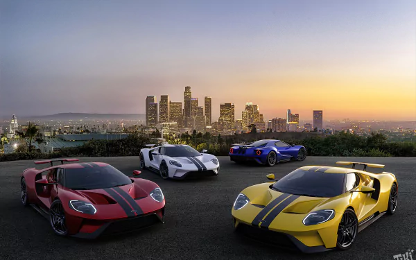 4K Ultra HD desktop wallpaper: four Ford GT supercars (yellow, white, blue, red) parked on a rooftop overlooking a city skyline at sunset.