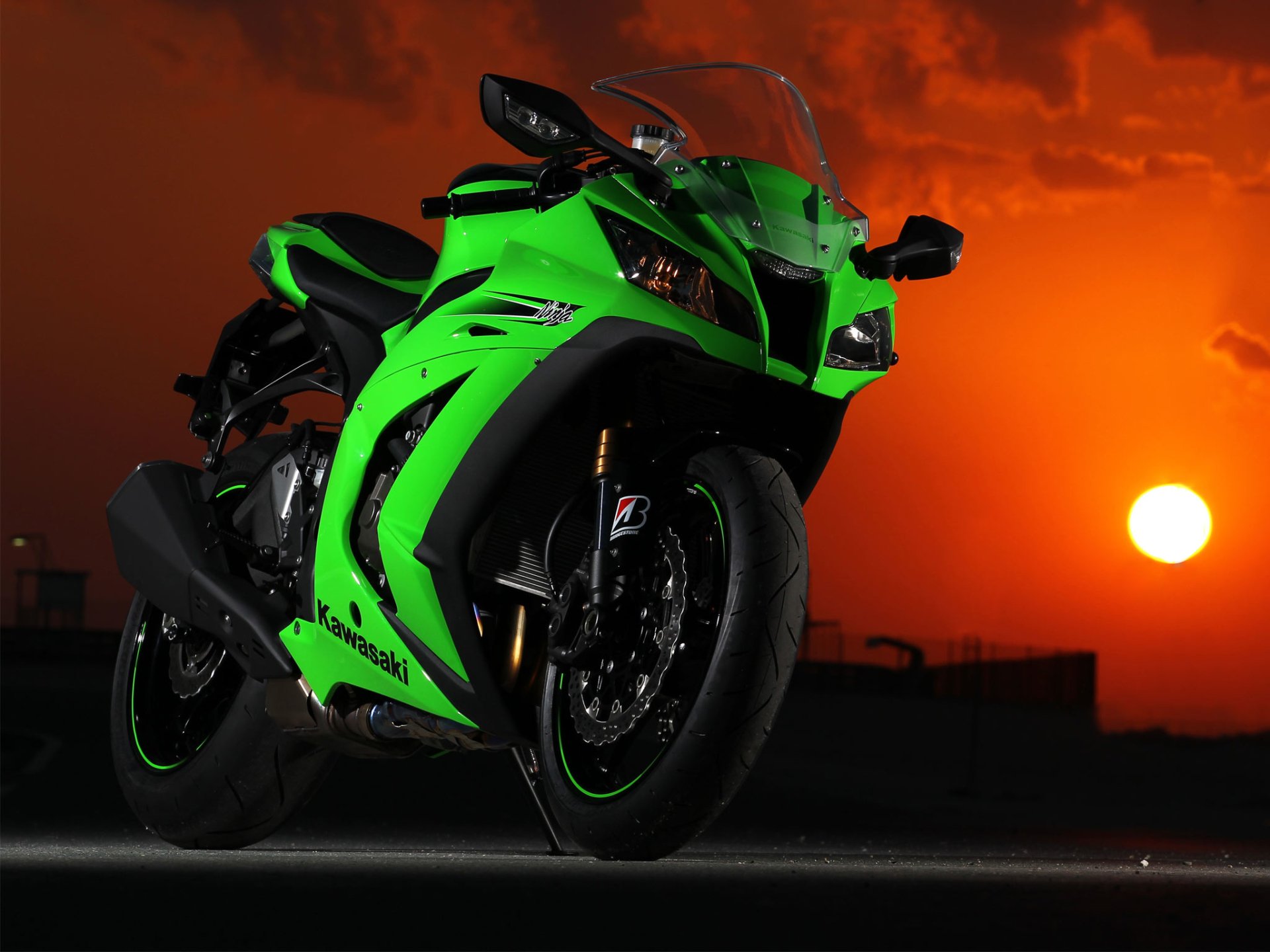 HD desktop wallpaper of a Kawasaki Ninja motorcycle captured at sunset, with the vibrant orange sky providing a striking backdrop to the sleek, green vehicle.