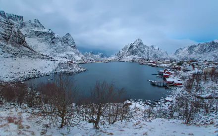 Snow-covered mountains surround the tranquil bay at Reine in Norway’s Lofoten Islands, captured in a serene HD desktop wallpaper photograph.