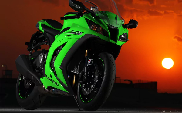 HD desktop wallpaper of a Kawasaki Ninja motorcycle captured at sunset, with the vibrant orange sky providing a striking backdrop to the sleek, green vehicle.