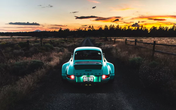 Teal Porsche seen from the rear driving along a rural road at sunset, warm sky and fences — 5K Ultra HD PC desktop wallpaper.