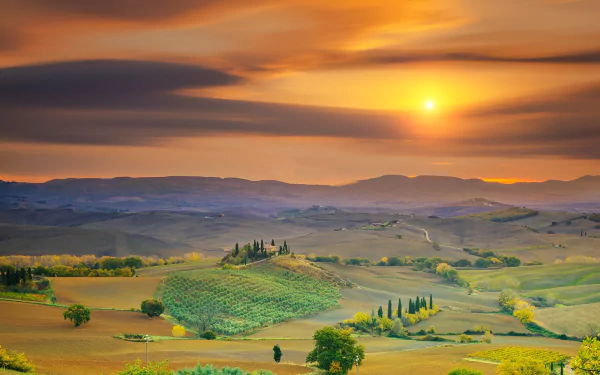 Panoramic HD desktop wallpaper of Tuscany, Italy at sunset showcasing rolling hills, scattered trees, and vibrant sky colors in this stunning landscape photography.