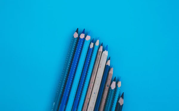 HD desktop wallpaper featuring a close-up photograph of sharpened blue and gray pencils arranged on a bright blue background.