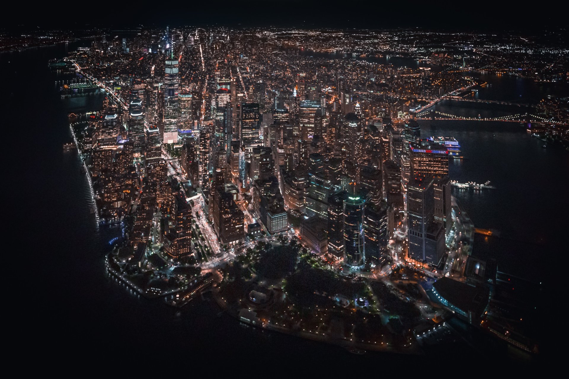 Aerial night view of New York City skyline with illuminated skyscrapers and streets, captured as a high-definition man-made urban scene for PC desktop wallpaper.
