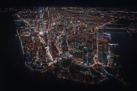 Aerial night view of New York City skyline with illuminated skyscrapers and streets, captured as a high-definition man-made urban scene for PC desktop wallpaper.